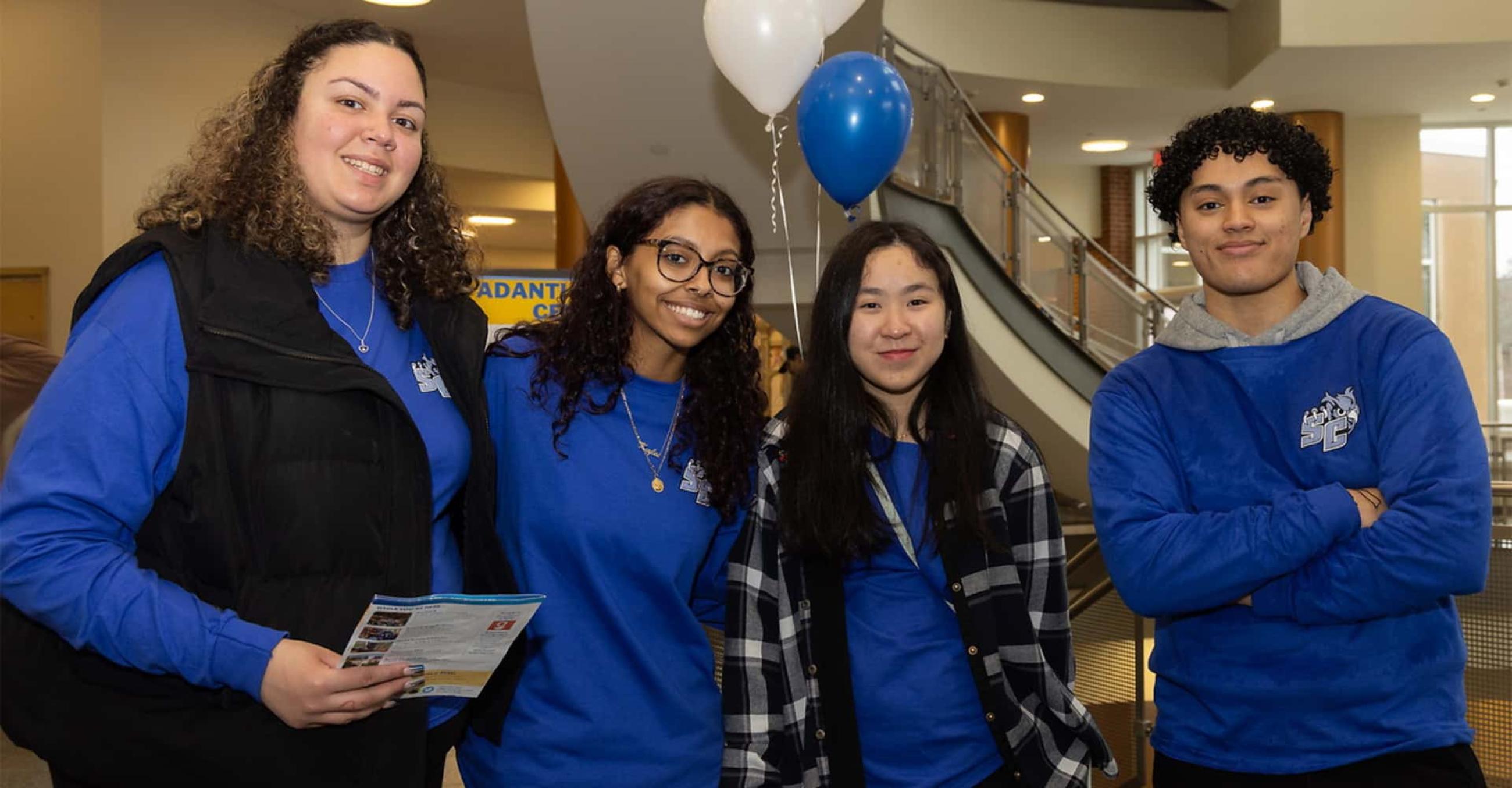 a group of four students standing together in the student center