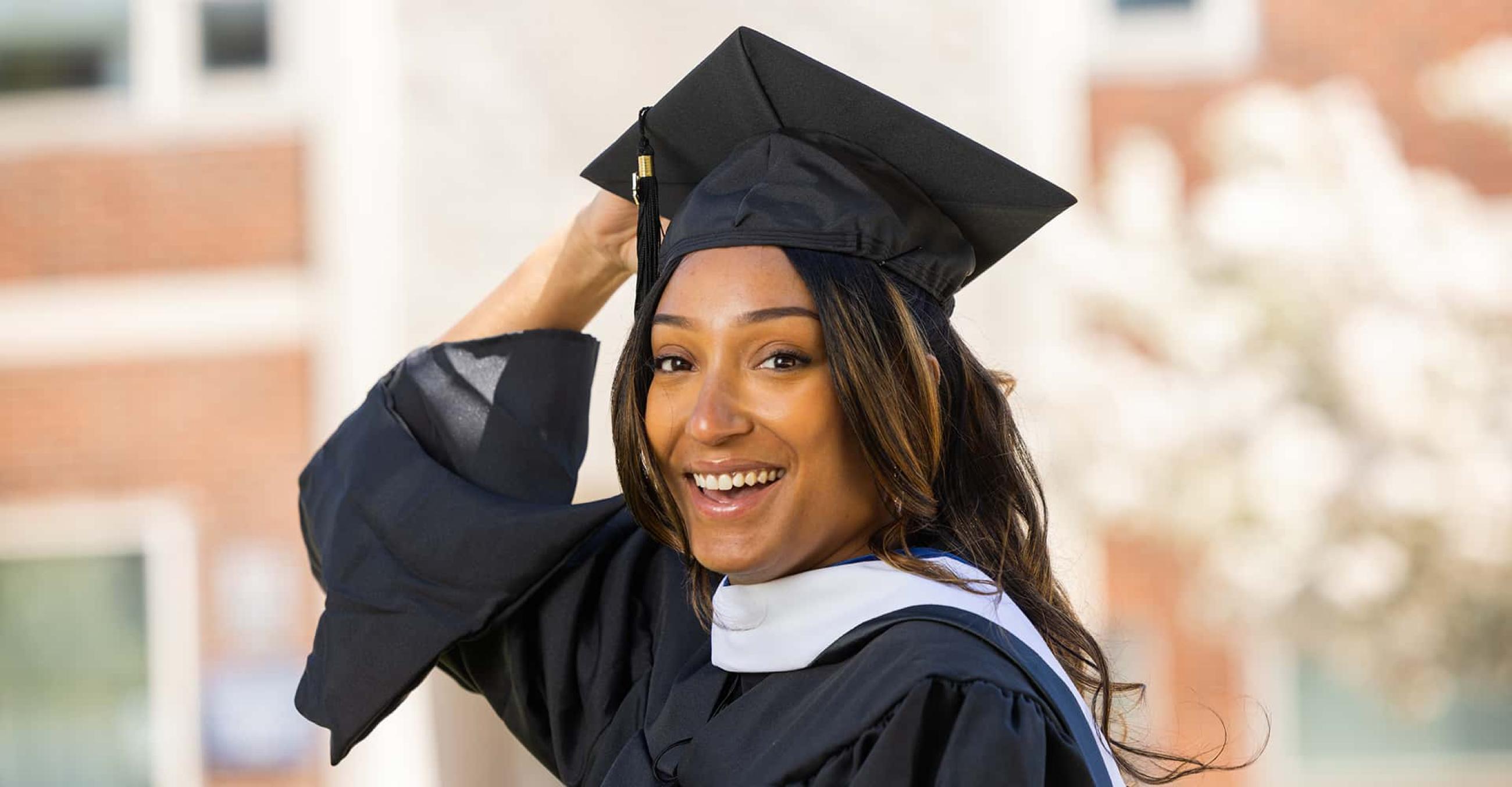 a student in cap and gown smiles at the camera