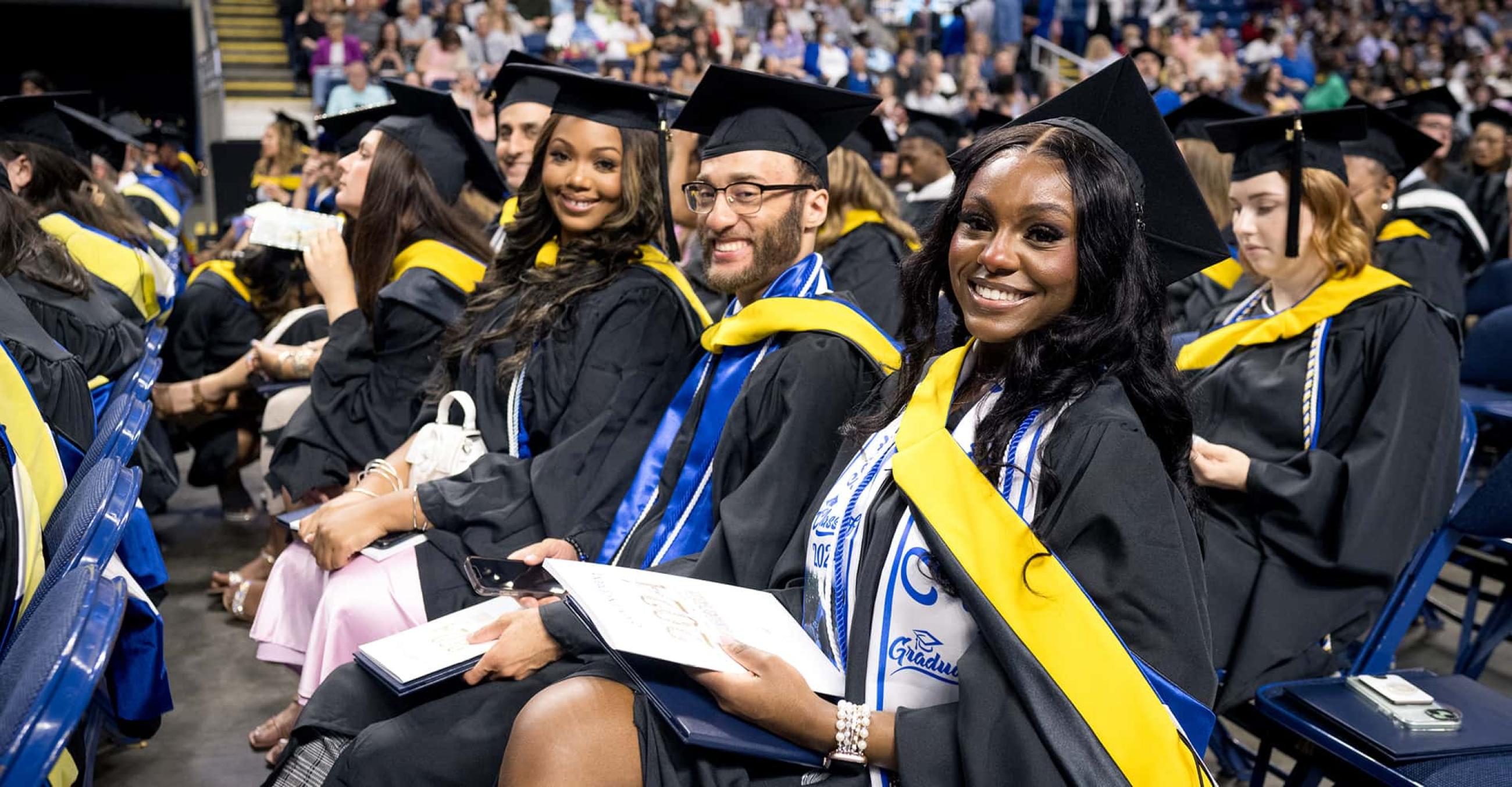 a group of graduates in caps and gowns smile at the camera