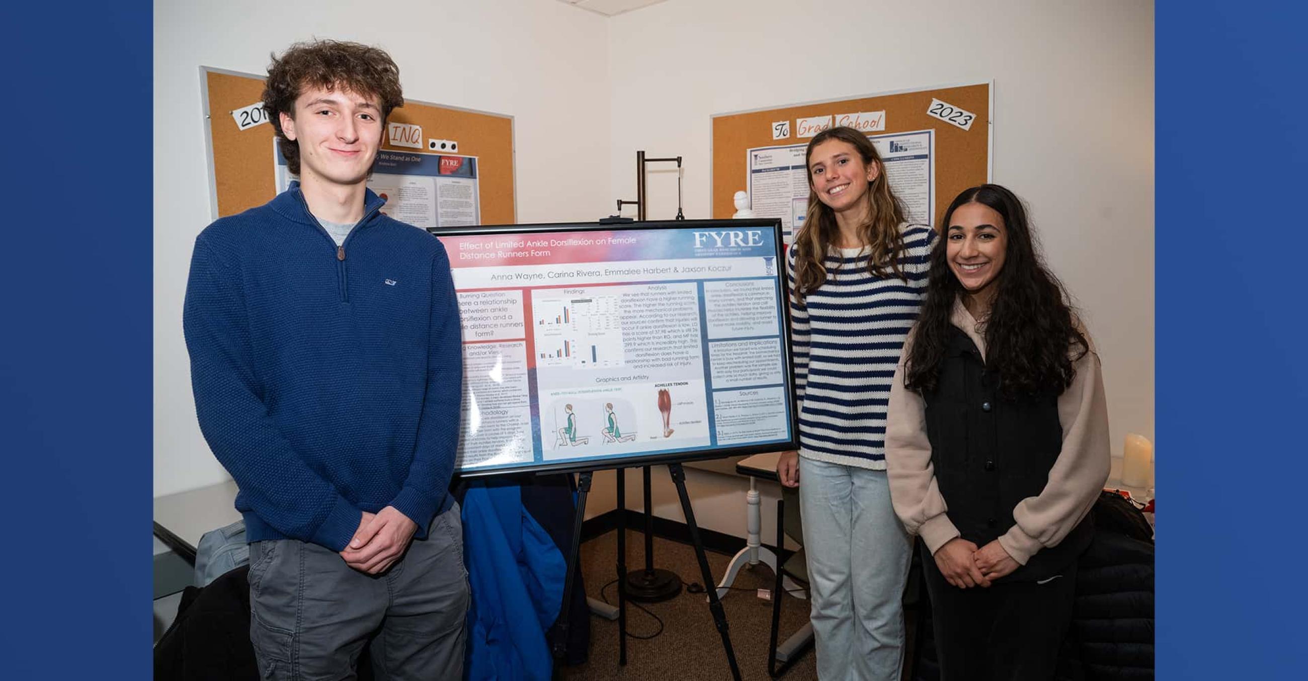 three students stand beside their poster presentation