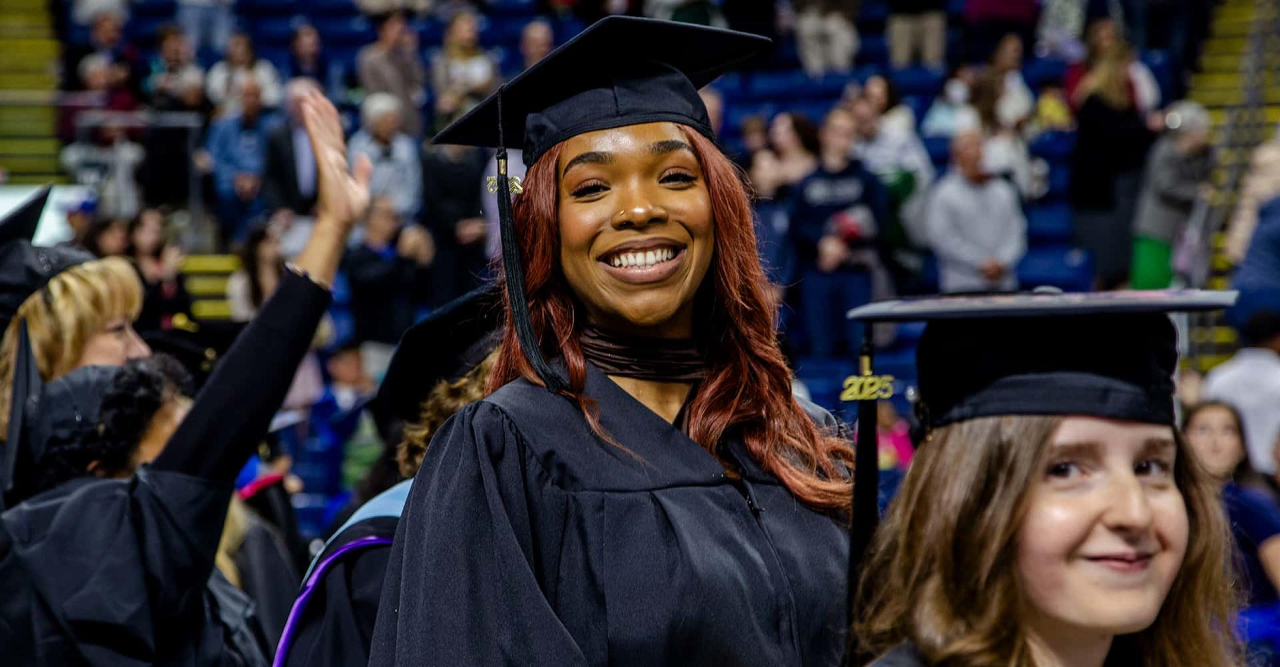 two women in graduation caps and gowns smile at the camera
