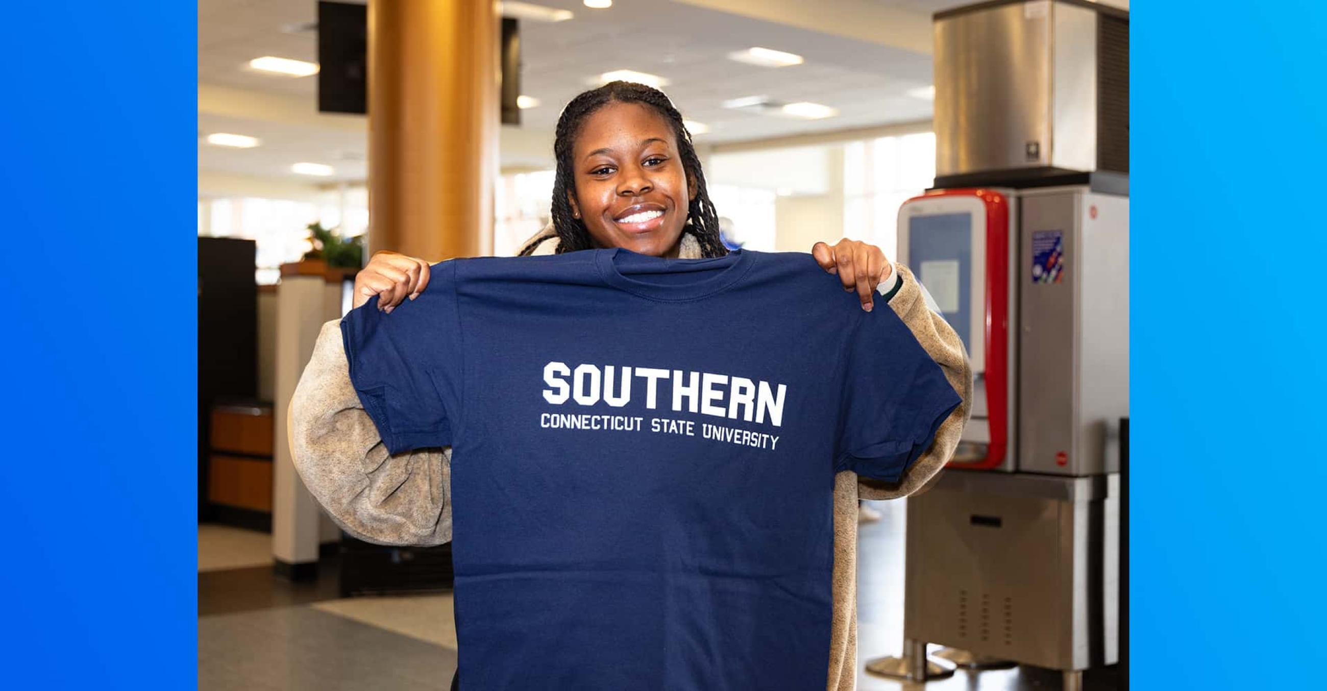 smiling student holds up a Southern t-shirt