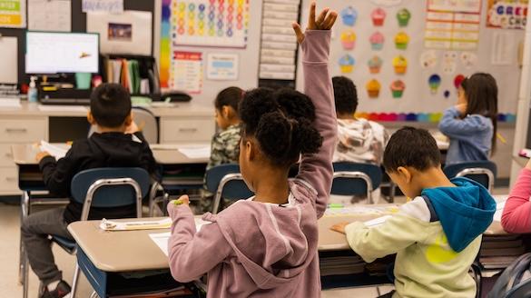 Elementary school students with one raising her hand