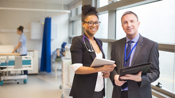 two healthcare administrators standing in front of a hospital room