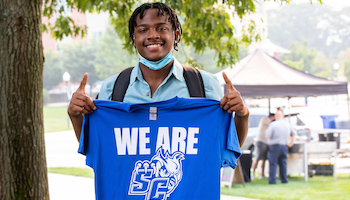 A student holding a 'We are SC' SCSU shirt
