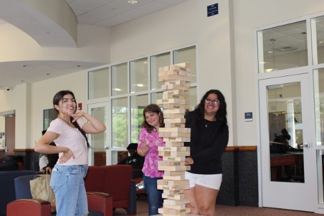 A group of three girls playing jumbo Jenga in the Adanti Student Center.
