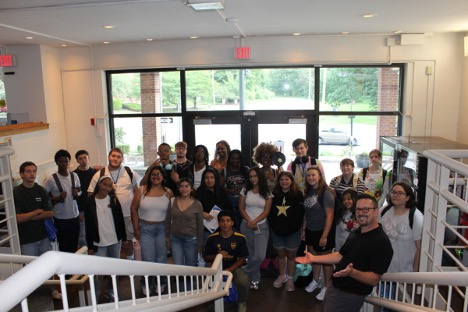 A group of students standing for a picture in front of a stairwell in a living hall during the Summer Institute Program.