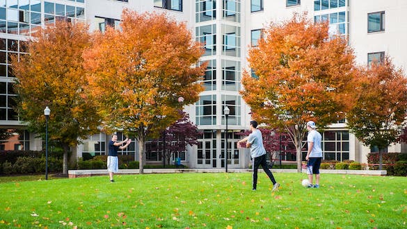 Students playing football outside of a residence hall dorm